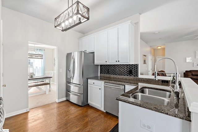 kitchen featuring a sink, white cabinets, appliances with stainless steel finishes, dark stone countertops, and dark wood finished floors