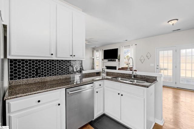 kitchen featuring visible vents, a peninsula, a sink, white cabinetry, and stainless steel dishwasher