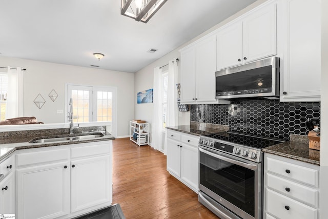 kitchen featuring visible vents, appliances with stainless steel finishes, wood finished floors, white cabinetry, and a sink