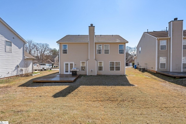 rear view of house featuring a yard, central AC unit, and a chimney