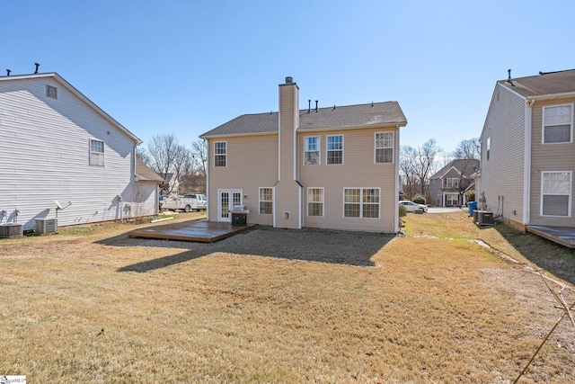 rear view of property featuring central AC, a chimney, and a lawn