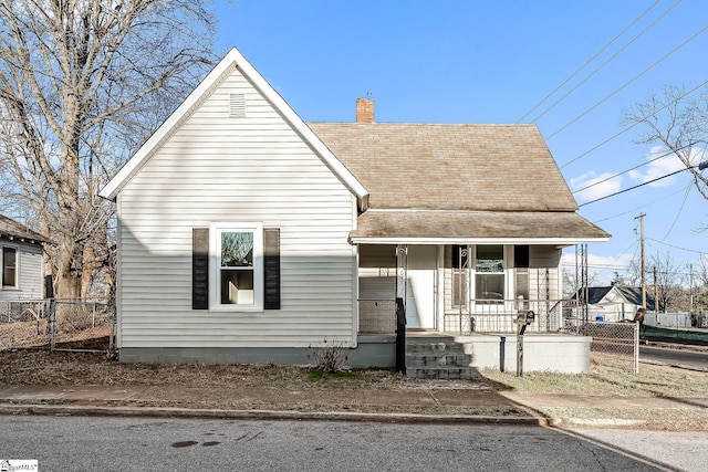 bungalow-style home featuring a porch, roof with shingles, fence, and a chimney