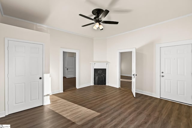 unfurnished living room with a ceiling fan, dark wood finished floors, a fireplace, and crown molding