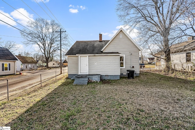 rear view of house with entry steps, a lawn, a chimney, crawl space, and fence