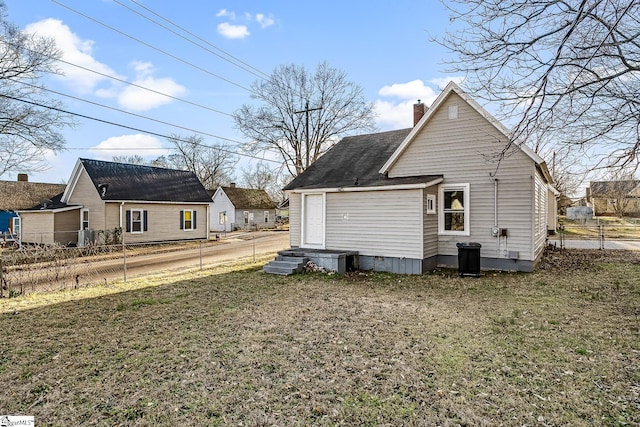 rear view of property with a shingled roof, a lawn, a chimney, crawl space, and fence