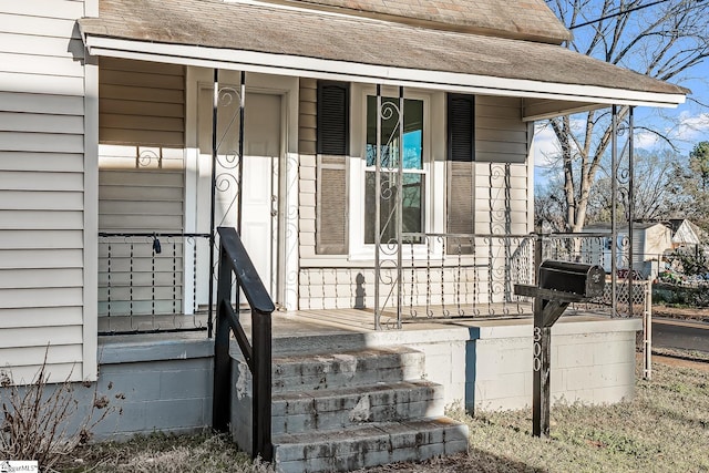 property entrance featuring covered porch and roof with shingles