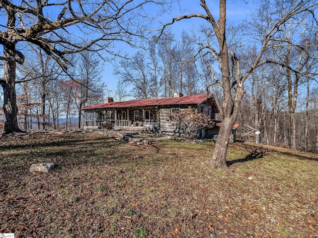 view of front of house featuring a chimney, a front yard, and a sunroom