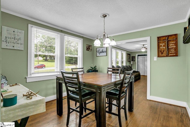 dining space with a textured ceiling, ornamental molding, wood finished floors, and baseboards