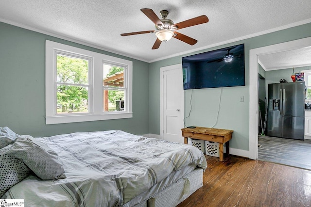 bedroom with a textured ceiling, wood finished floors, a ceiling fan, stainless steel refrigerator with ice dispenser, and crown molding