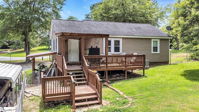 rear view of house with roof with shingles, a yard, fence, a wooden deck, and central AC