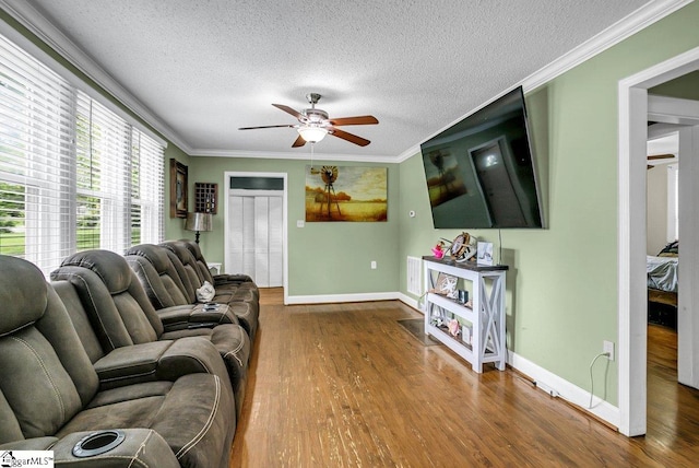 living area featuring ornamental molding, ceiling fan, baseboards, and wood finished floors