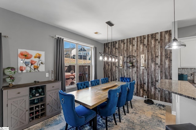 dining space with baseboards, visible vents, and wooden walls