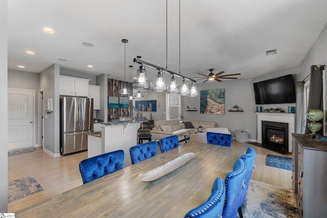 dining room with ceiling fan, recessed lighting, a fireplace with flush hearth, and light wood-style floors