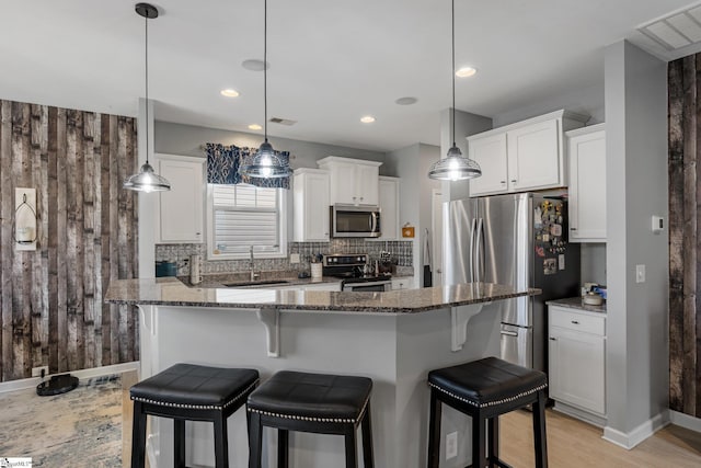 kitchen featuring a sink, stainless steel appliances, a kitchen bar, and backsplash