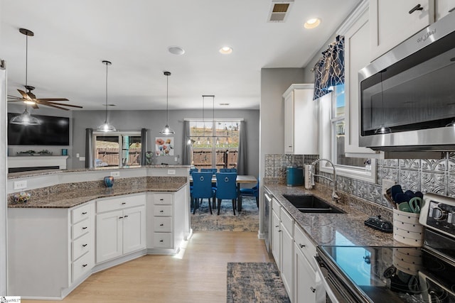 kitchen with light wood-style flooring, a sink, visible vents, appliances with stainless steel finishes, and decorative light fixtures