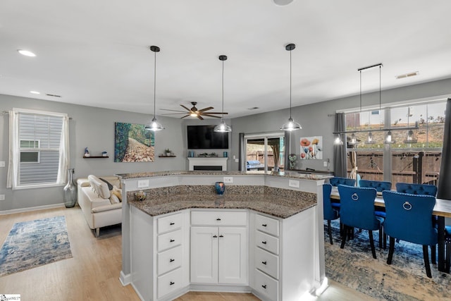 kitchen with light wood-type flooring, visible vents, open floor plan, and dark stone counters