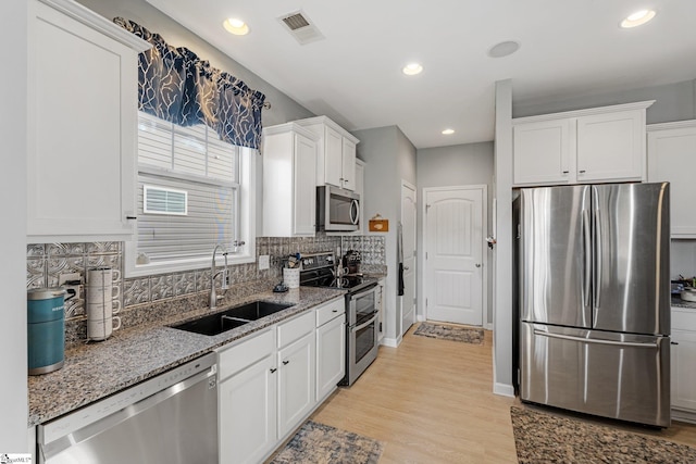 kitchen featuring stone countertops, a sink, visible vents, white cabinets, and appliances with stainless steel finishes