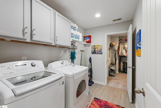 clothes washing area with washing machine and clothes dryer, cabinet space, visible vents, light wood-type flooring, and baseboards