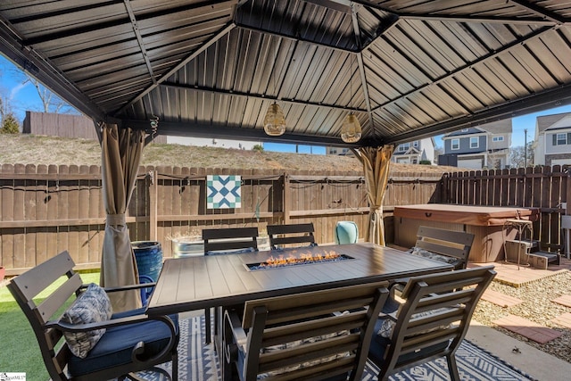 view of patio / terrace with an outdoor fire pit, outdoor dining area, fence, and a gazebo