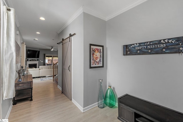 hall featuring light wood-style floors, baseboards, and a barn door