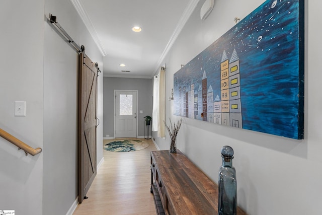 corridor with recessed lighting, light wood-style flooring, a barn door, ornamental molding, and baseboards