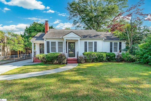 view of front of home featuring a shingled roof, a chimney, fence, and a front lawn