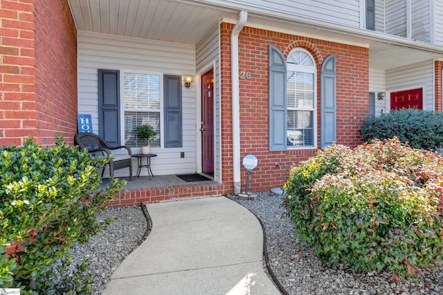 property entrance featuring a porch and brick siding