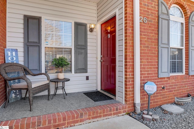 property entrance with a porch and brick siding