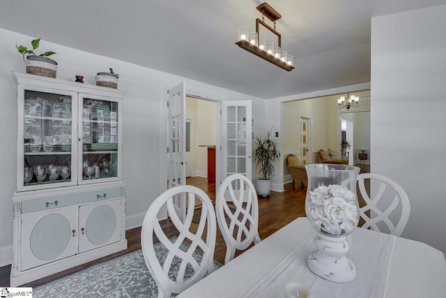 dining area with lofted ceiling, baseboards, a chandelier, and wood finished floors