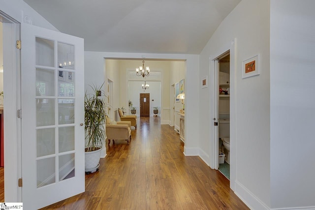 interior space featuring lofted ceiling, a notable chandelier, dark wood finished floors, and baseboards