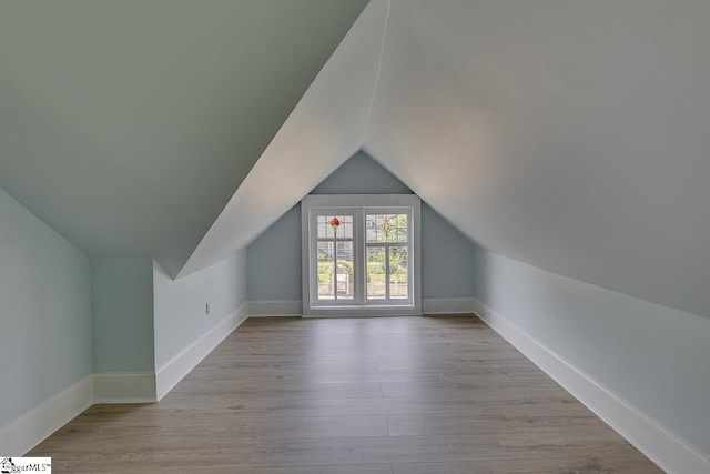 bonus room with baseboards, vaulted ceiling, and wood finished floors