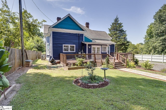 back of house with a wooden deck, french doors, a fenced backyard, a chimney, and a yard