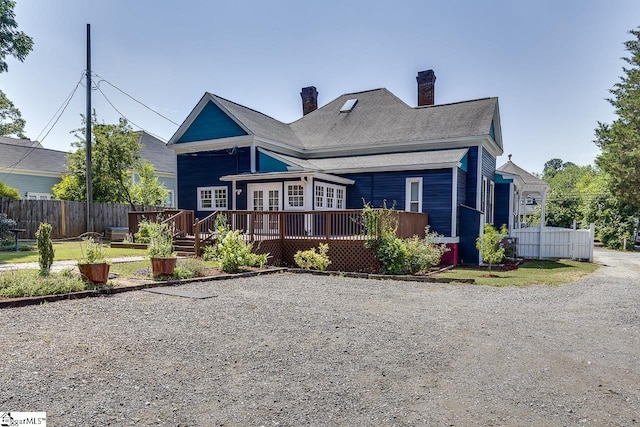 view of front of house with a chimney, fence, and a wooden deck