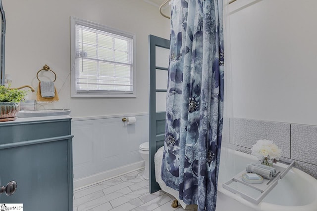 bathroom featuring toilet, vanity, marble finish floor, wainscoting, and a shower with curtain