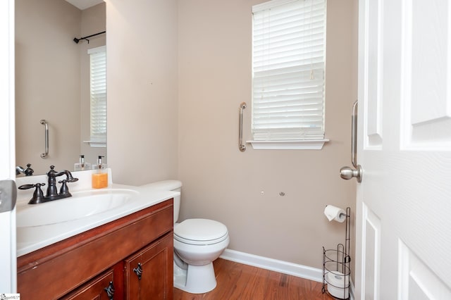 bathroom with toilet, baseboards, wood finished floors, and vanity