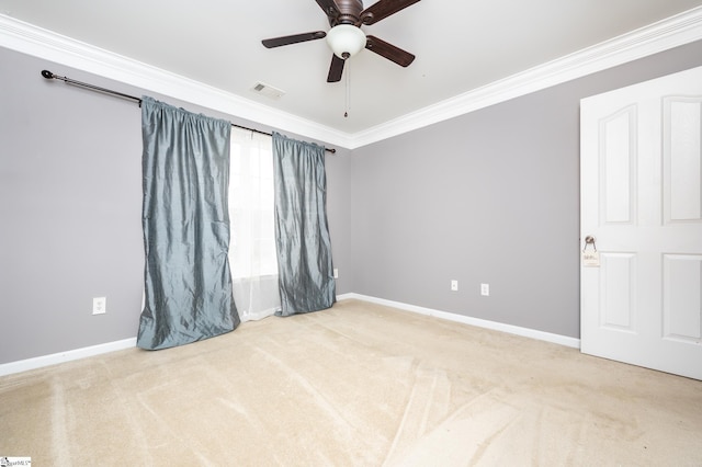 carpeted empty room with ornamental molding, a ceiling fan, visible vents, and baseboards