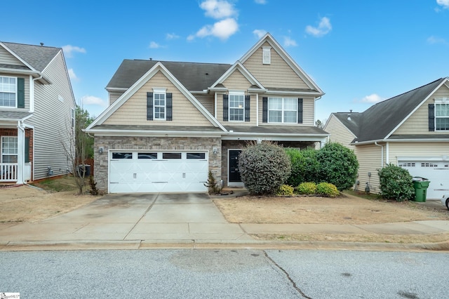 view of front facade featuring driveway, stone siding, and a garage