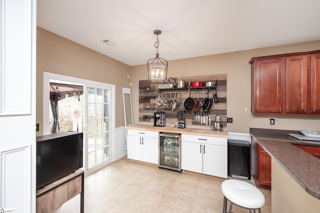 kitchen with wine cooler, dark countertops, visible vents, hanging light fixtures, and decorative backsplash