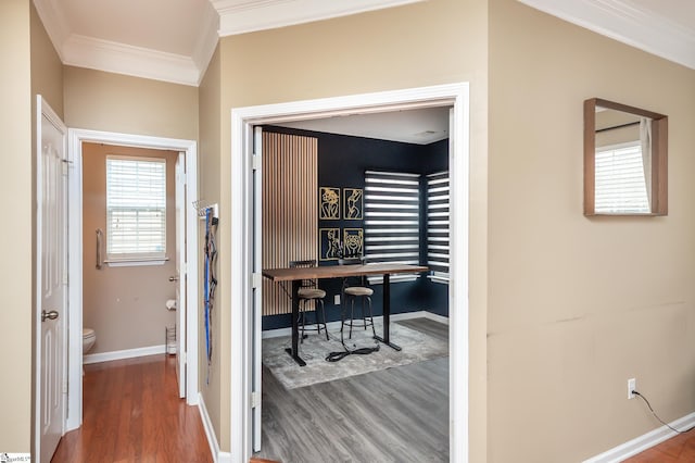 hallway featuring baseboards, ornamental molding, and wood finished floors