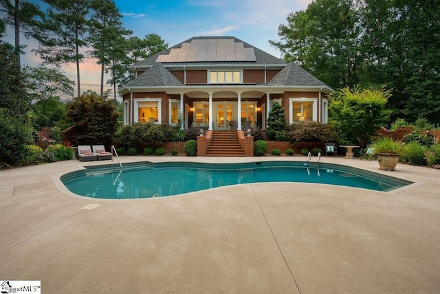 1212 Stillwater Dr, Seneca, SC 29678 - back of property at dusk featuring roof mounted solar panels, a patio area, an outdoor pool, and stairway