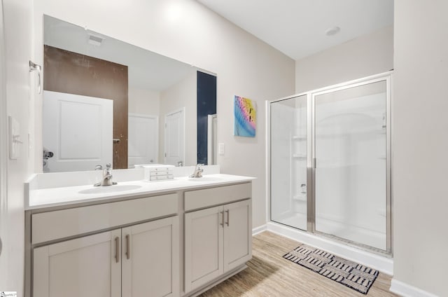 bathroom featuring wood finished floors, a stall shower, and a sink