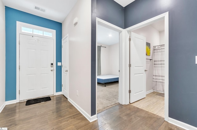 entrance foyer featuring baseboards, visible vents, and wood finished floors