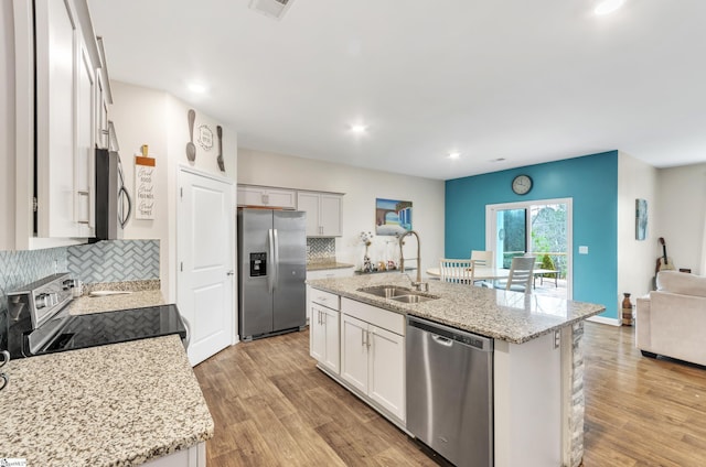 kitchen featuring stainless steel appliances, light wood-type flooring, a sink, and tasteful backsplash