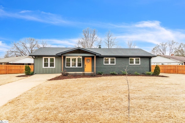 view of front of home with board and batten siding, crawl space, brick siding, and fence