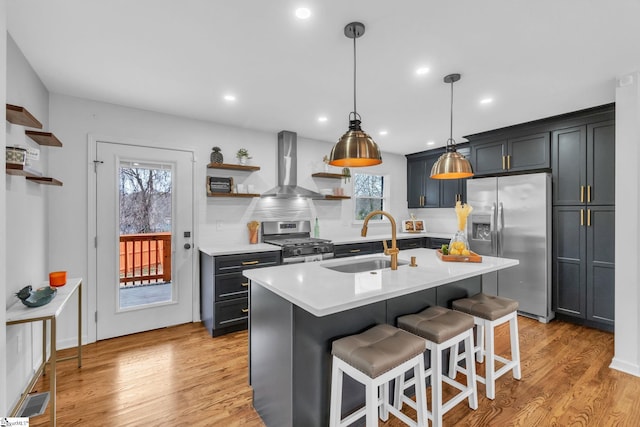 kitchen with appliances with stainless steel finishes, light countertops, wall chimney range hood, open shelves, and a sink