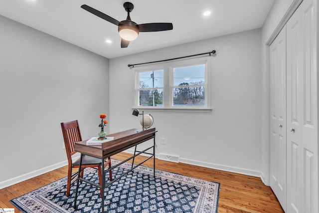 office space featuring a ceiling fan, light wood-style flooring, visible vents, and baseboards