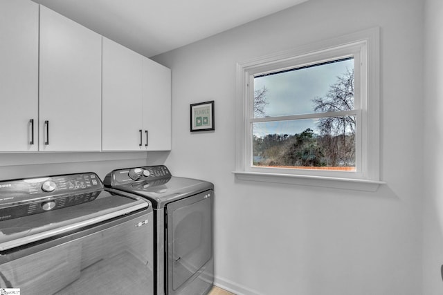 washroom with cabinet space, baseboards, and washing machine and clothes dryer