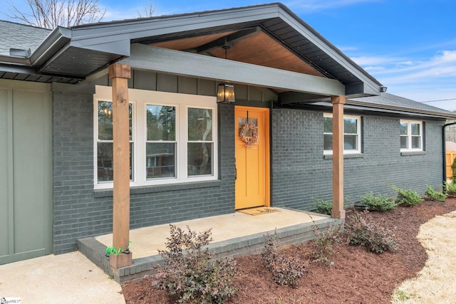 doorway to property featuring board and batten siding and brick siding