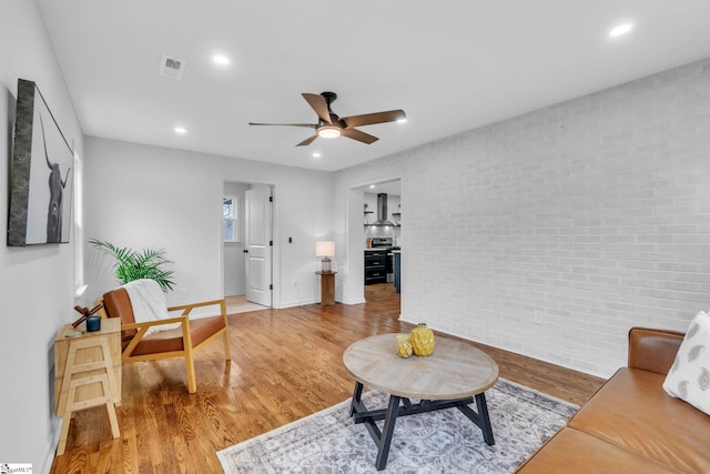 living room featuring recessed lighting, visible vents, light wood-style floors, a ceiling fan, and brick wall