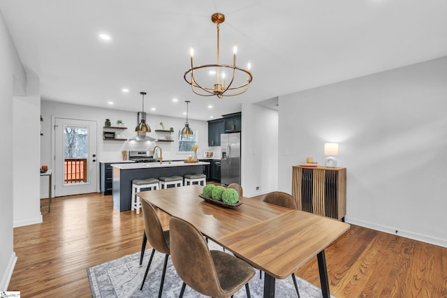 dining room featuring a chandelier, light wood-type flooring, and baseboards